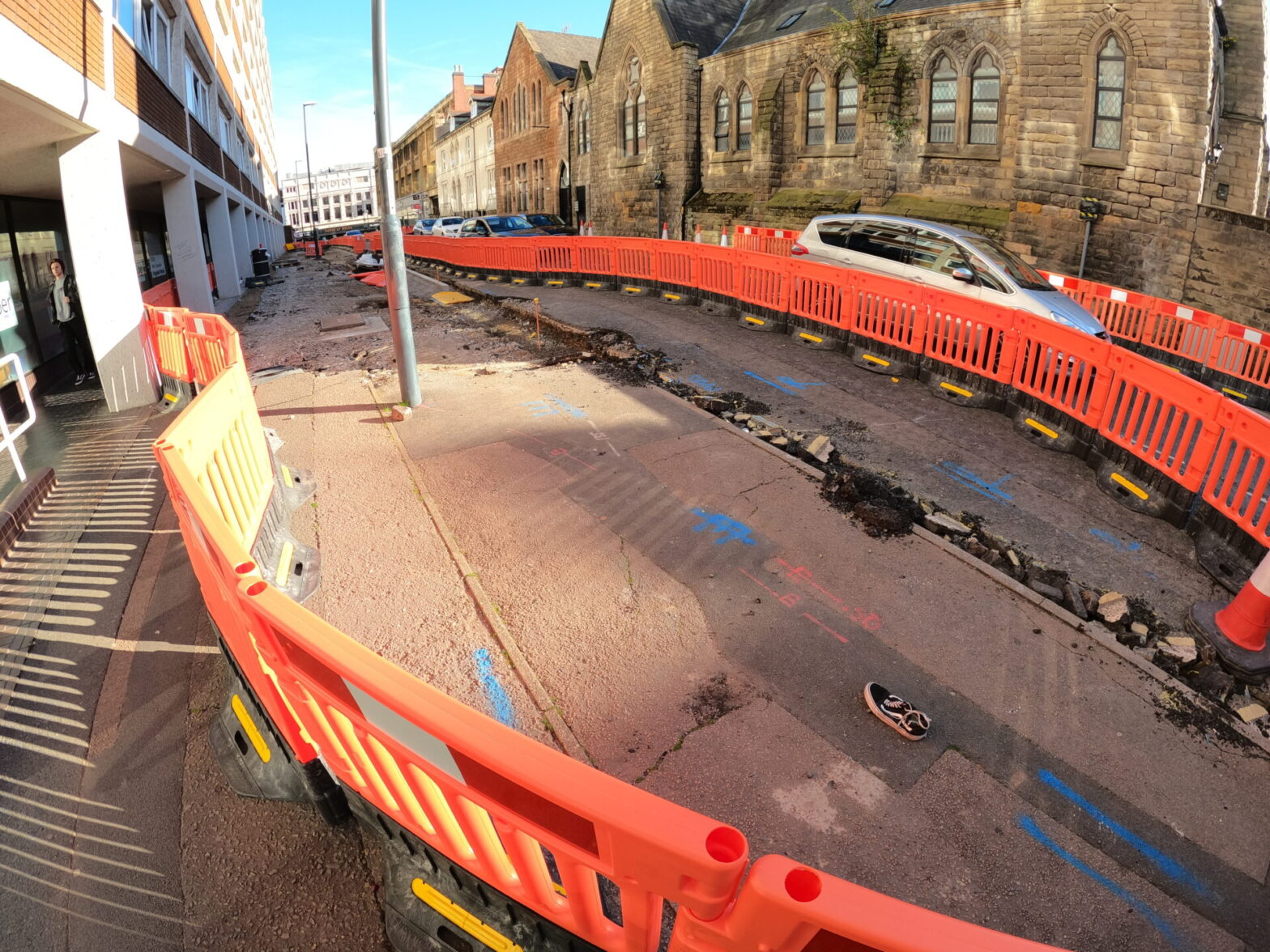 A street with surfacing and kerbs undergoing demolition protected by construction side pedestrian guard boards